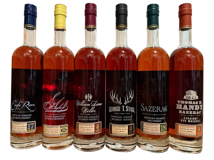 Six bottles of different whiskeys arranged on a wooden surface.